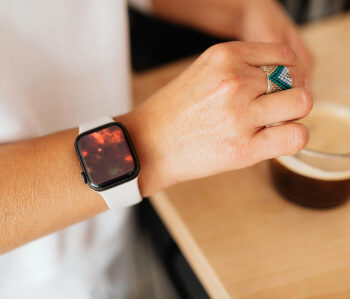 Person wearing apple watch with gold and blue ring. apple watch had a photograph of cremation photography package with red solar flakes with a blue solar flake