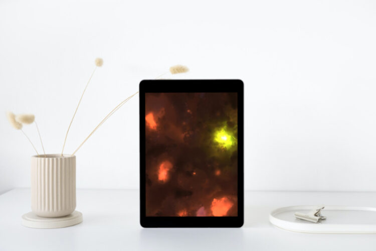 White wall and counter with a beige jar of 3 cattails, an ipad, and white jar with binder clip. Ipad has a digital picture of the cremation photography.